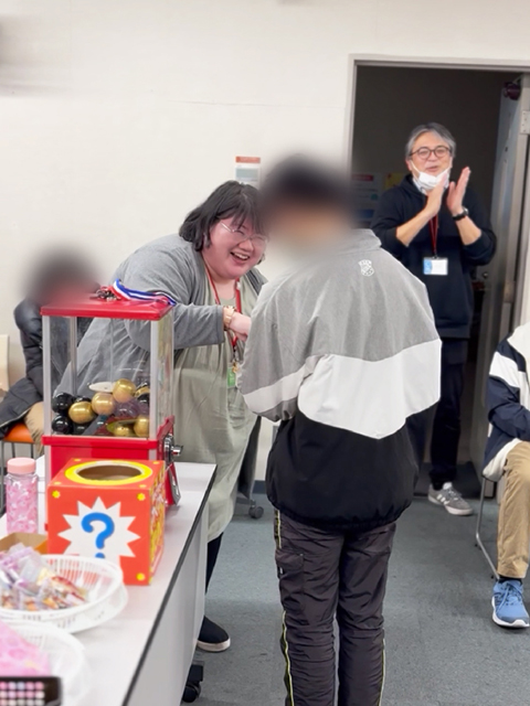 障害者雇用創造センターレクリエーション風景「投げリンピック」景品のガチャガチャをもらう様子