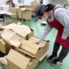 段ボールを前に入荷を取る女性スタッフ