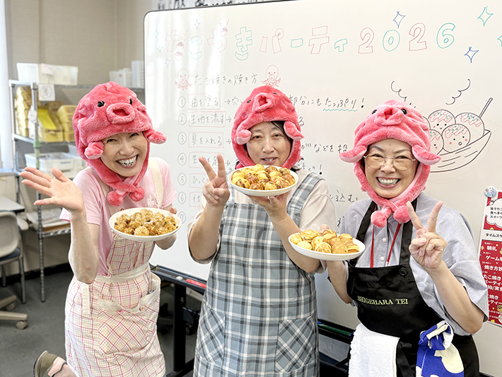 障碍者ITカレッジ愛西で開催された『たこ焼きパーティー』。完成品を手に取るスタッフの集合イメージ