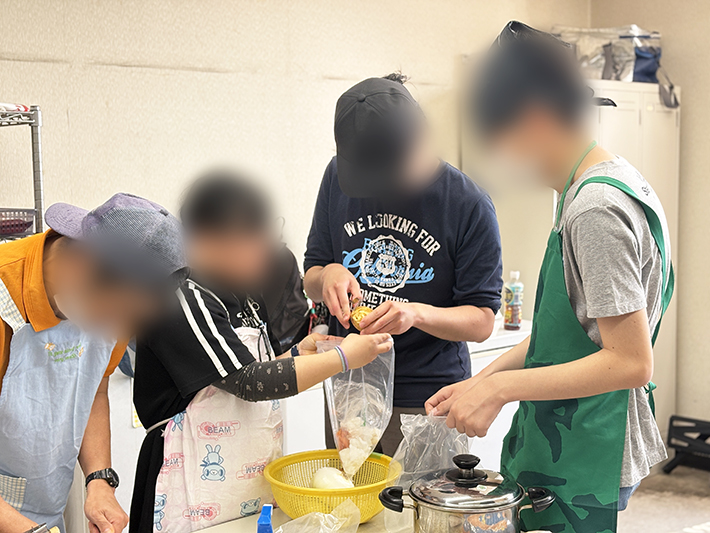 ピーラーを使い、チームで協力しながら大量のジャガイモの皮を丁寧に剥いていく作業風景。