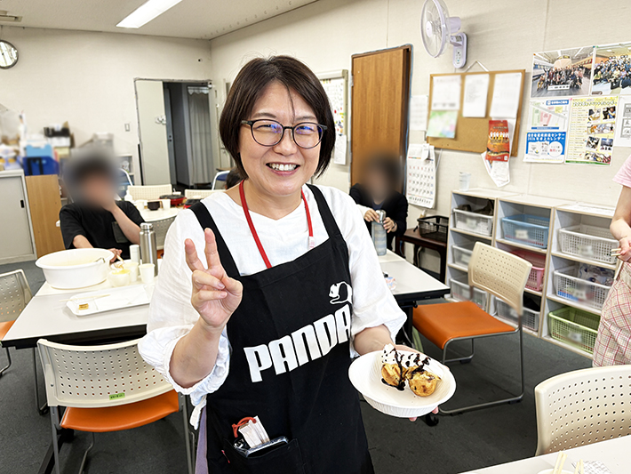 完成したスイーツ風たこ焼き(チョコ&ホイップ)を手に微笑むスタッフ。参加者に大好評だったアレンジメニューの紹介