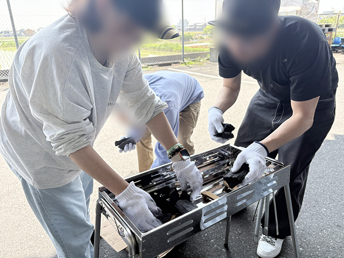 BBQコンロに木炭を並べ、効率よく火が回るように配置を調整している準備段階の写真。