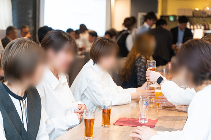 懇親会の各テーブルで、拠点や部署の垣根を超えてスタッフ同士が笑顔で乾杯し、親睦を深める様子