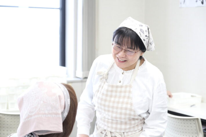 作業訓練中、利用者様に明るく声をかけ見守るスタッフ。日々の何気ないコミュニケーションを大切にし、自信を持って取り組める環境を創造する支援の現場