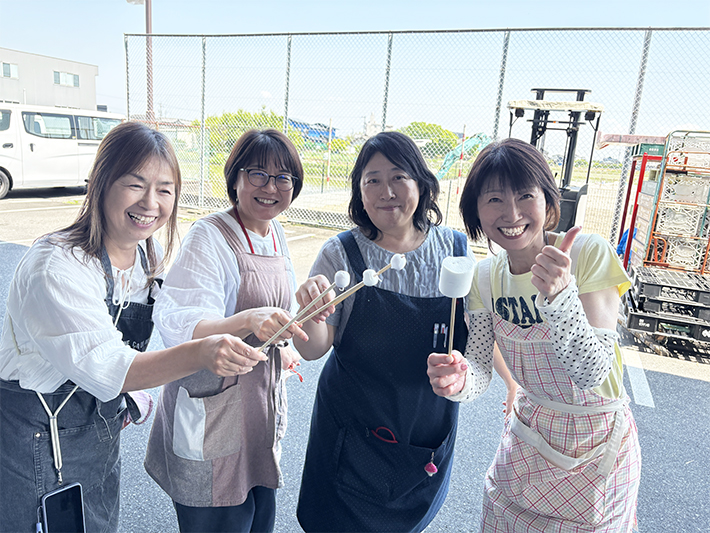 イベントを支えるスタッフたちが、マシュマロ串を手に団結力を感じさせる笑顔の集合写真。
