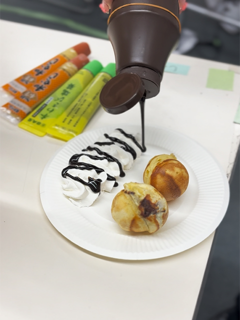 焼き上がったチョコたこ焼きにホイップクリームを添える仕上げの工程。見た目も豪華なスイーツの完成