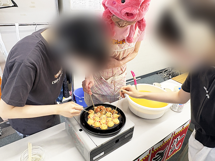 実際にたこ焼き作りに挑戦する訓練生。千枚通しを使い、自分たちの手でくるりと生地をひっくり返す真剣な表情
