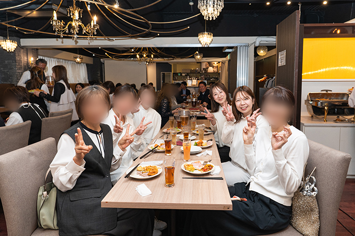 会場の華やかな料理を囲み、共にビジョンを共有する仲間たちと記念撮影に応じるスタッフの晴れやかな表情