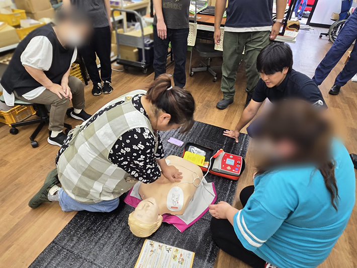 いざという時に利用者の命を守るため、オリーブのスタッフが力強く正確なリズムで胸骨圧迫を行い、救命スキルを確認する場面。