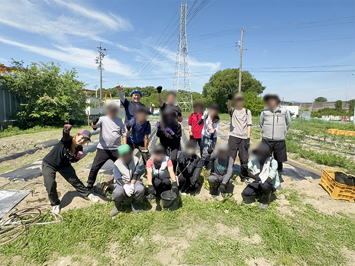 2026年6月1日、フレーベル農園にて600本のさつまいもの苗植えを無事に終え、達成感あふれる笑顔で並ぶ訓練生とスタッフの集合写真。