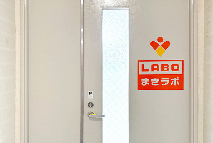 弥富市の作業スペース「まきラボ」の入り口の扉。GS2-24の正確な出力によって切り出されたカッティングシートを施工し、施設の顔となるロゴマークを美しく仕上げた様子。