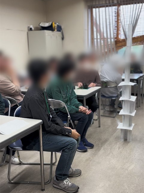自分たちが作り上げたタワーを見つめ、チームで一つのものを作り上げた達成感と、実際の業務にも通じる「協力の重要性」を実感する訓練生。