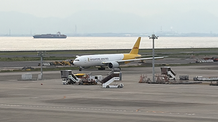 DHLの黄色いロゴが大きく描かれた、シンガポール航空の貨物専用機。世界を股にかける物流の要（かなめ）として、大型機ならではの迫力ある佇まい。