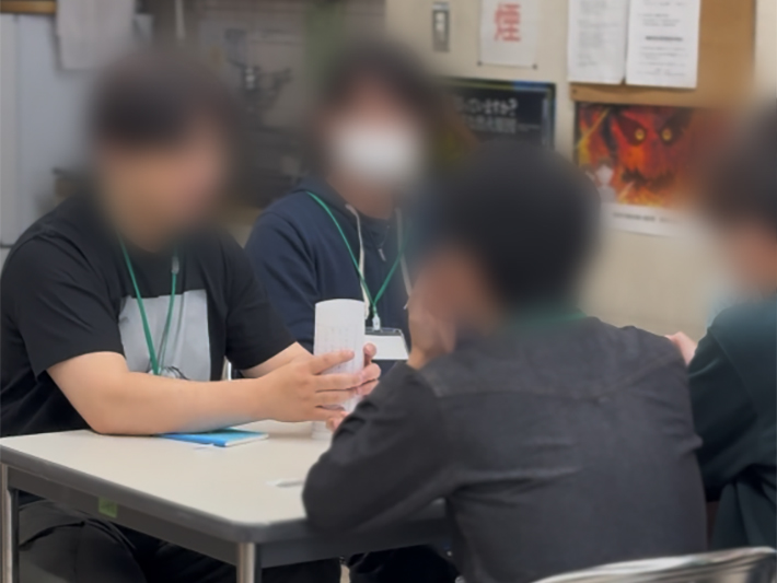 「どうすれば安定して高く積めるか」という課題に対し、メンバー同士が顔を合わせて積極的に意見を出し合うコミュニケーションの場面。