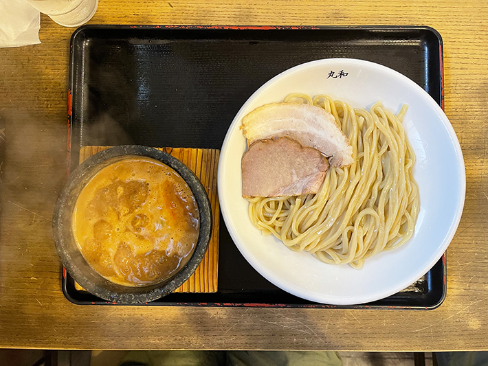 お店一番人気の「丸和つけ麺」。北海道産小麦の香りが引き立つ自家製麺に、分厚いチャーシューが2枚添えられている。石鍋に入った熱々の濃厚スープで、最後まで美味しく味わえる至福の一杯。