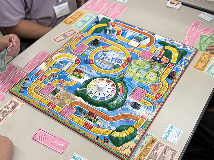 ゲーム序盤、結婚イベントを終えたばかりのプレイヤーたちがまだ互いに密集している盤面。5人プレイならではの「追突事故」が多発した、賑やかで波乱含みな展開を象徴する一枚。