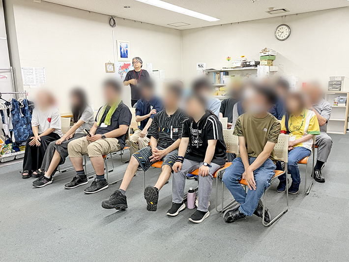 自分の順番を待ちながら、他の参加者の投球を「打倒スタッフ！」の掛け声とともに温かく見守る訓練生とスタッフ。事業所全体に一体感が生まれる、交流のひととき。