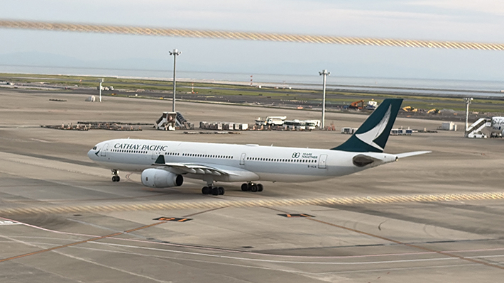 香港を代表するキャセイパシフィック航空の旅客機。洗練されたデザインの機体が、スカイデッキを訪れる見学客に海外旅行への憧れを抱かせる一コマ。