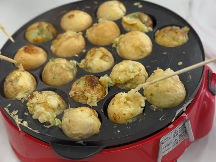 竹串を使い、たこ焼きを上手にくるくるとひっくり返す訓練生。周囲と声を掛け合いながら、綺麗な丸い形に焼き上げていく、集中力と手先の器用さが光る瞬間。