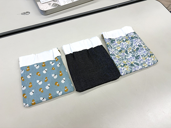 訓練生がそれぞれ選んだ個性豊かな布地で手作りした、完成品3つのバネ口ポーチ。色や絵柄がバラバラだからこそ「十人十色」の好みが光り、初めてぱかっと開いた時に「家族にプレゼントしよう」「何を入れて使おうかな」と笑顔がこぼれた手芸レクの輝かしい成果。