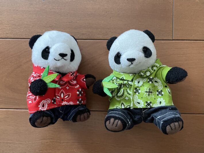 完成した赤色と緑色の夏らしい衣装を身にまとった2体のパンダのぬいぐるみ。週末の時間を使って一針一針丁寧に縫い上げ、手を動かして好きな形にしていく充実したひとときから生まれたハンドメイド作品。
