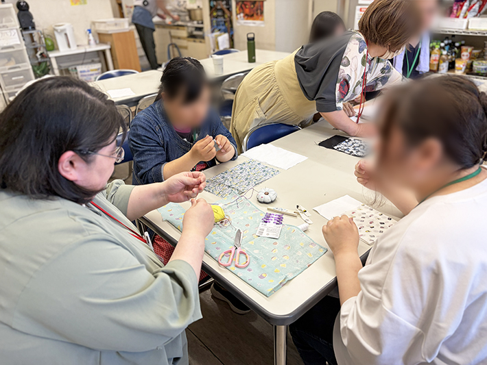 針仕事の途中で困ったところがあれば、作業支援員が適度な距離感を保ちながら助っ手としてサポートに入り、訓練生が安心して最後まで作りきれるようサポートする温かな指導風景。