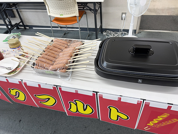 鉄板の傍らに美しく並べられた、焼く前のジューシーなフランクフルトの数々。これから香ばしく焼き上げられる肉厚のフランクフルトに、お腹を空かせた訓練生たちの熱い視線が集まる準備風景。