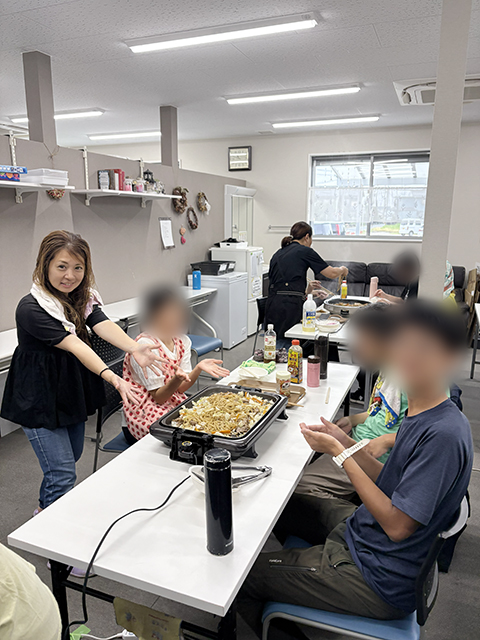 テーブルの上にドカンと出来上がった、ソースが均一に絡んで湯気が立ち上る美味しそうな焼きそば。みんなで協力して作り、できたての焼きそばを「美味しいね!」とワイワイいただく、幸せな食事シーン。