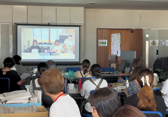 ロールプレイ動画の視聴後、気づいた点や違和感をワークシートに真剣にペンで書き込んでいるグループワークの手元風景。自身の普段の支援を振り返り、何が不適切だったのか、どう改善すべきかを個人ワークで整理している場面。