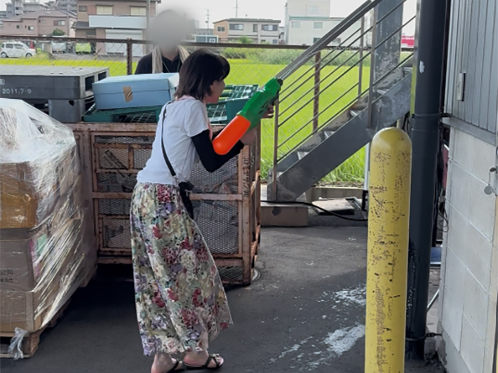 流しそうめんを美味しくいただいた後の、お楽しみイベントである「水鉄砲対戦」のワンシーン。訓練生もスタッフも童心に返り、勢いよく水鉄砲を構えて水を掛け合いながら、夏の暑さを吹き飛ばして大笑いしている爽快な一瞬。