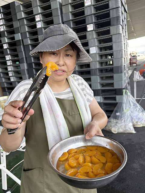 デザートやトッピング用として、缶詰のみかんを大きなボウルにたっぷりとあけ、トングを使って取り出している様子。そうめんに彩りと爽やかな甘みを添え、みんなに喜んでもらうための下準備のひとコマ。