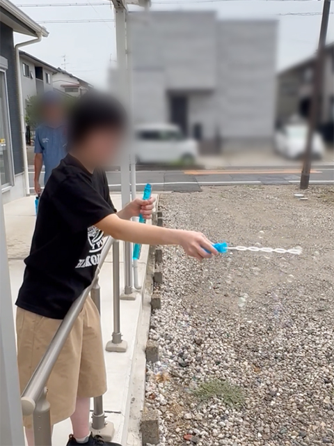 風に乗ってキラキラと空へ舞い上がっていくシャボン玉が、夏の終わりのレクリエーションを穏やかに彩っている夏祭りのワンシーン。