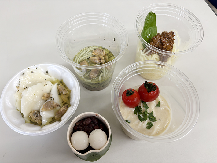 冷製ボンゴレや豆乳ジャージャー麺風など、各自がお気に入りのつけダレに取り分けたそうめんや具材。そうめんだけでなく、プチトマトや白玉、一口サイズのお餅など、ナベ'sキッチンならではのバラエティ豊かなトッピングが並ぶ賑やかなお皿。