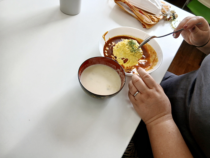 自分で作った出来立てのふわとろオムライスとあたたかいスープを、テーブルでスプーンを使って大満足で味わう昼食の様子。「美味しくできた！」と笑顔がこぼれる、手作り料理レクリエーションならではの楽しい食事風景。