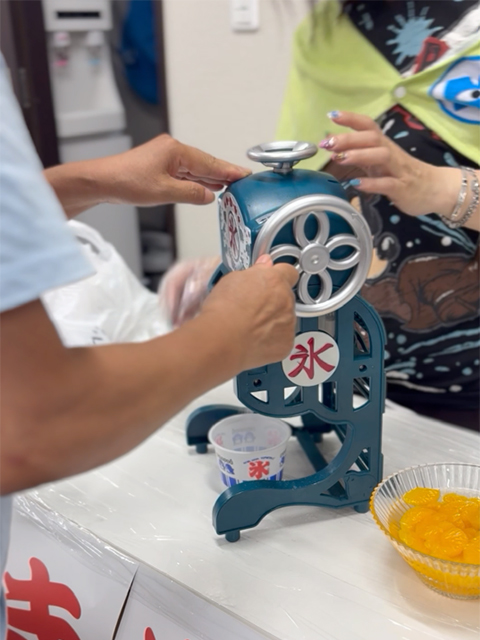 かき氷器を使い、涼しげな音を立てながらシャリシャリと冷たくてふわふわの氷を削り出している製氷シーン。夏祭りらしさをさらに盛り上げる、ひんやりスイーツコーナーの人気アトラクション。