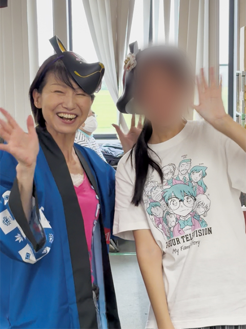 お気に入りのお面を頭につけ、お祭りの楽しさを全身で感じながら弾けるような笑顔を見せるスタッフと訓練生。日常の訓練を離れ、仲間やスタッフと共に最高の夏の思い出を作る、心温まる素晴らしいレクリエーションのひととき。