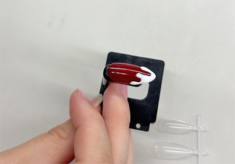 深みのあるボルドーカラーに白いソースがとろりと垂れたような立体的なデザインを施した個性的で可愛らしいネイルチップ作品。