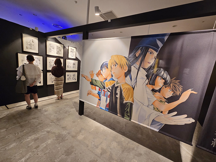 来場者が原画を鑑賞する姿と、ヒカル・佐為・アキラ・和谷・伊角ら主要キャラクターが描かれた大型カラータペストリー。