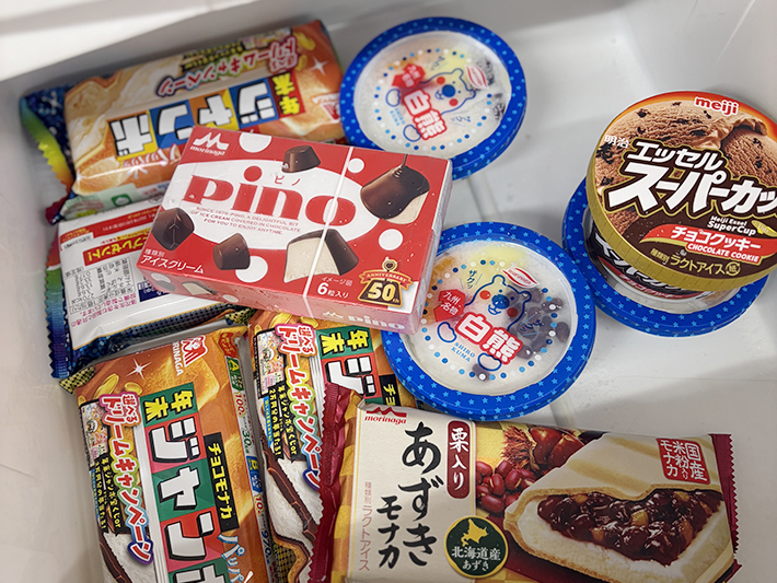 愛西事業所の「オフィスろーたす」で1個100円にて販売されている人気アイスクリームの各種パッケージ。チョコモナカジャンボやpino、白熊、エッセルスーパーカップなどが保冷ボックス内に並び、まきの木の皆さんが食後に楽しむ至福のひとときを伝える写真。