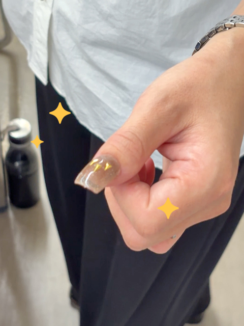 完成したネイルチップを自分の爪にあてがい、サイズやデザインの仕上がりを確認している手元写真。