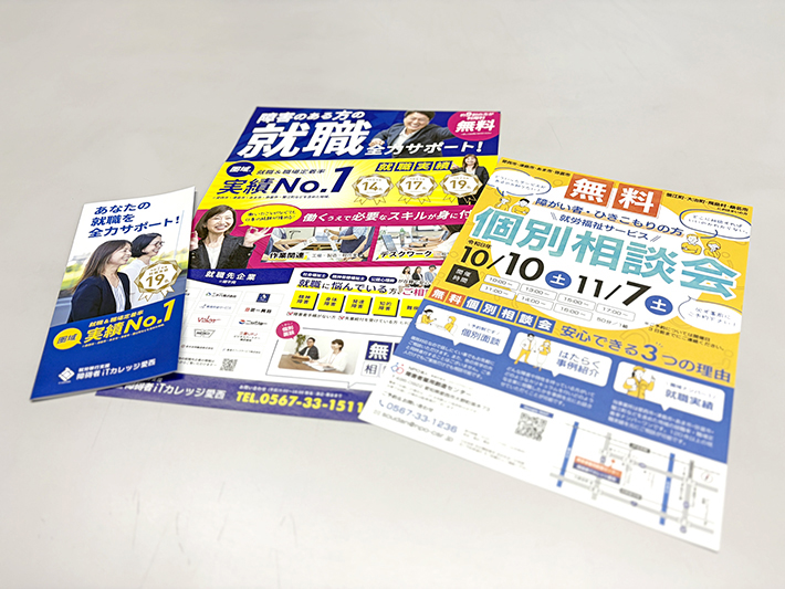 事業所の取り組みや無料個別相談会、就労実績をまとめた各種案内チラシや三活パンフレットがテーブルに並べられている様子。地域の方々や支援を必要とする方へ情報を届けるために作成された広報チラシ類。