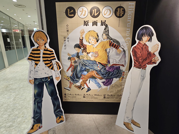 「ヒカルの碁 原画展」のメインビジュアルポスターと、等身大パネルで並ぶ主人公・進藤ヒカルとライバル・塔矢アキラの入口展示。