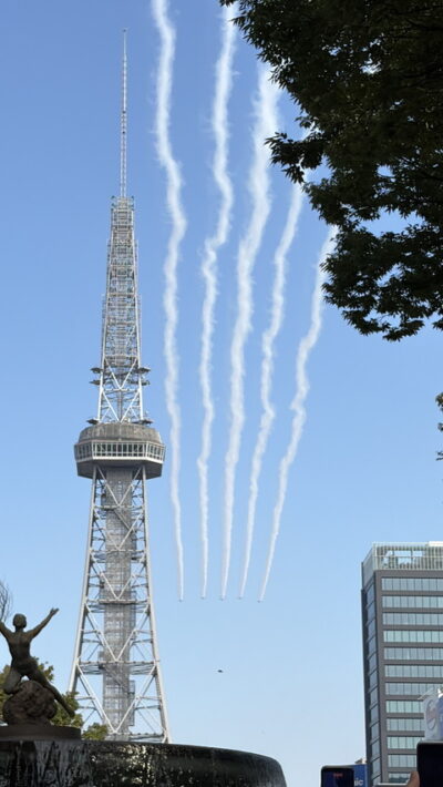 テレビ塔の横の青空に、ブルーインパルスが引いた5本の白い煙