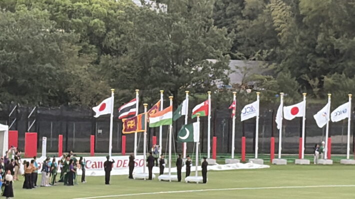 グラウンドに各国の旗が並ぶ国旗掲揚のセレモニー。日本、インド、スリランカ、パキスタンなどの旗が見える