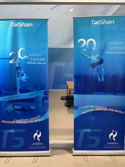 第20回アジア競技大会のオフィシャルスポンサー「TaiShan」のロールアップバナー2枚。体操選手の写真と「CHAMPION QUALITY」の文字